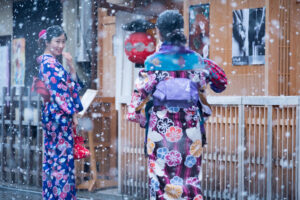 Friends wearing kimono enjoy photographing each other during a snow shower in the Gion district of Kyoto.
